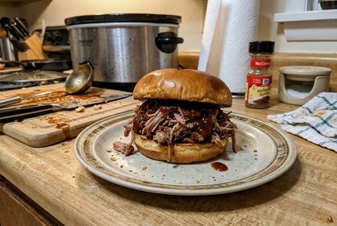 Crockpot pulled pork sandwich piled high with barbecue sauce on a bun