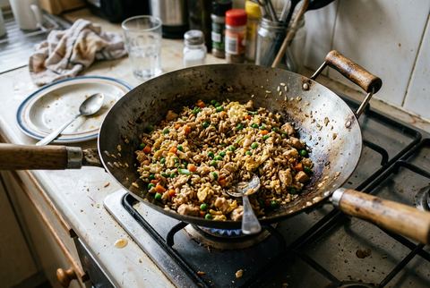 Chicken fried rice with egg, peas, and carrots in a wok
